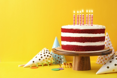 Photo of Delicious homemade red velvet cake with candles on yellow background. Space for text