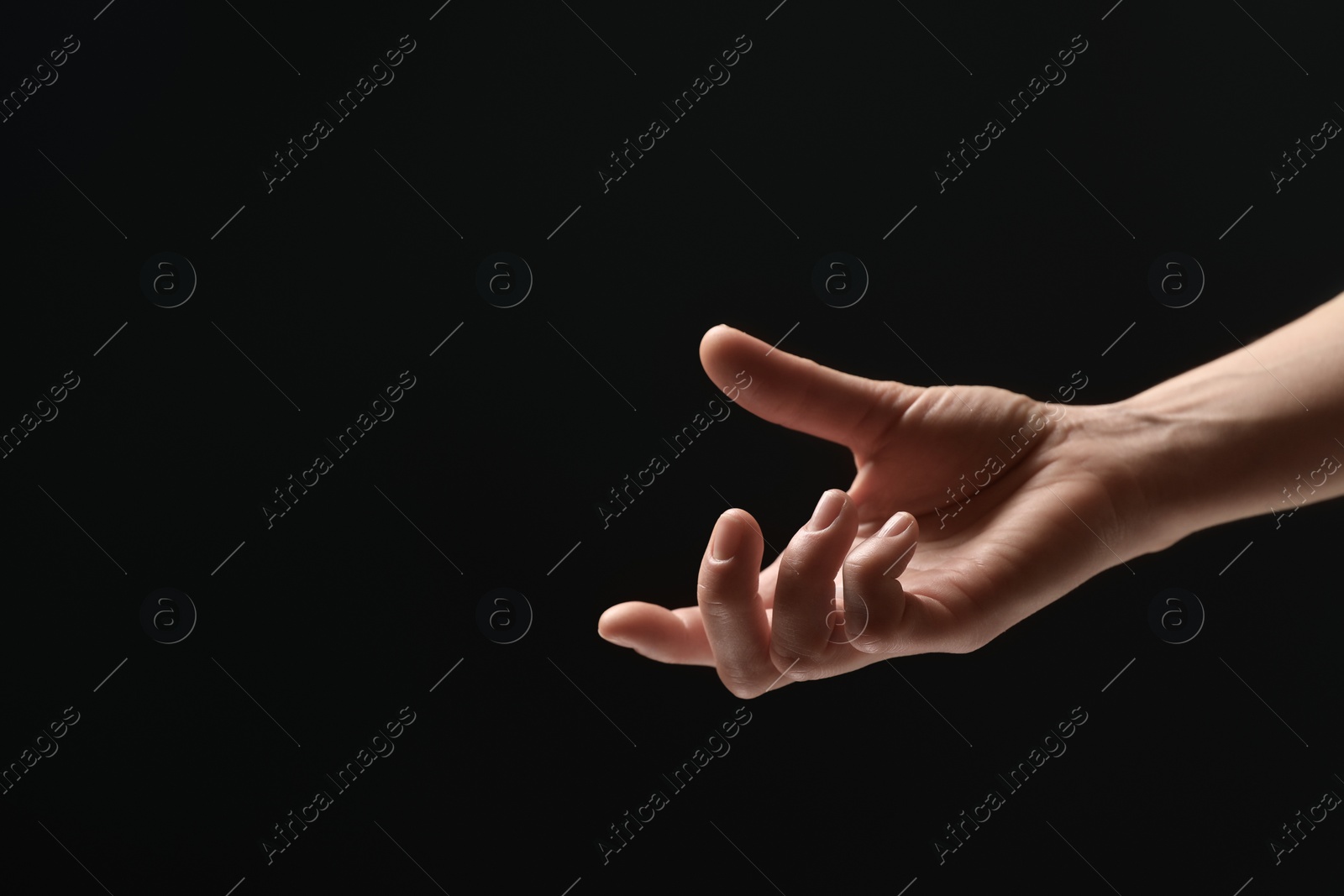 Photo of Woman holding something in hand on black background, closeup. Space for text