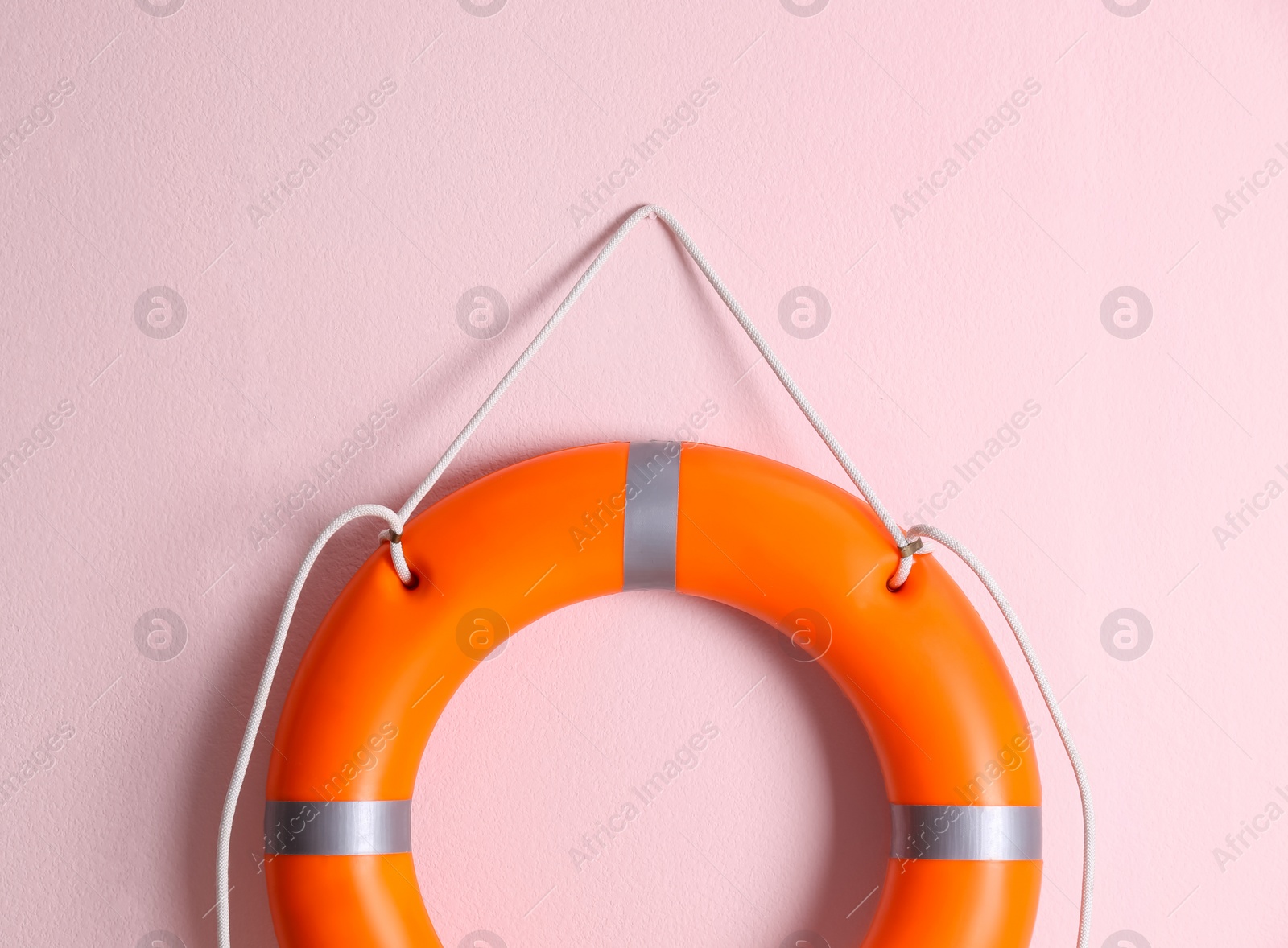 Photo of Orange lifebuoy on pink background. Rescue equipment