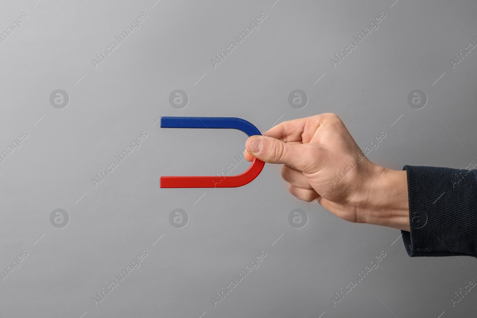 Photo of Man holding magnet on grey background, closeup. Space for text