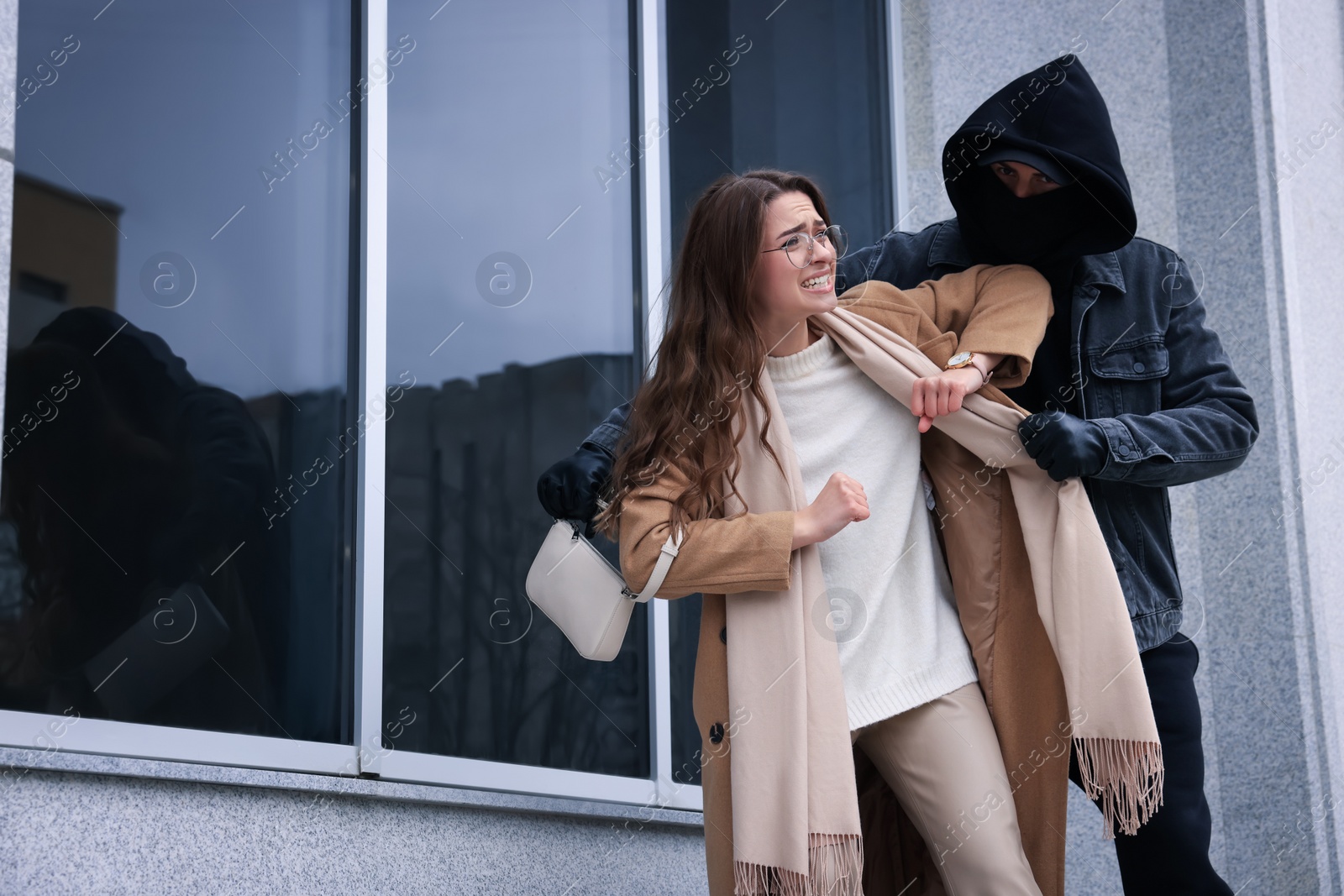 Photo of Woman fighting with thief while he trying to steal her bag near building, space for text. Self defense concept