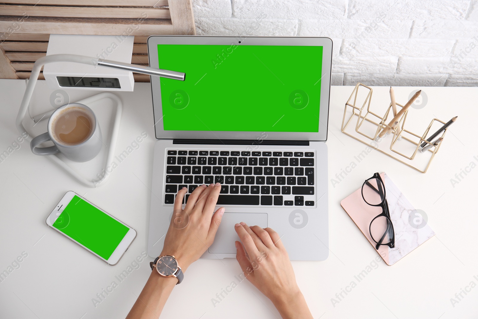 Image of Young woman using laptop at white desk, top view. Device display with chroma key