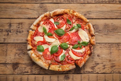 Photo of Delicious Caprese pizza on wooden table, top view