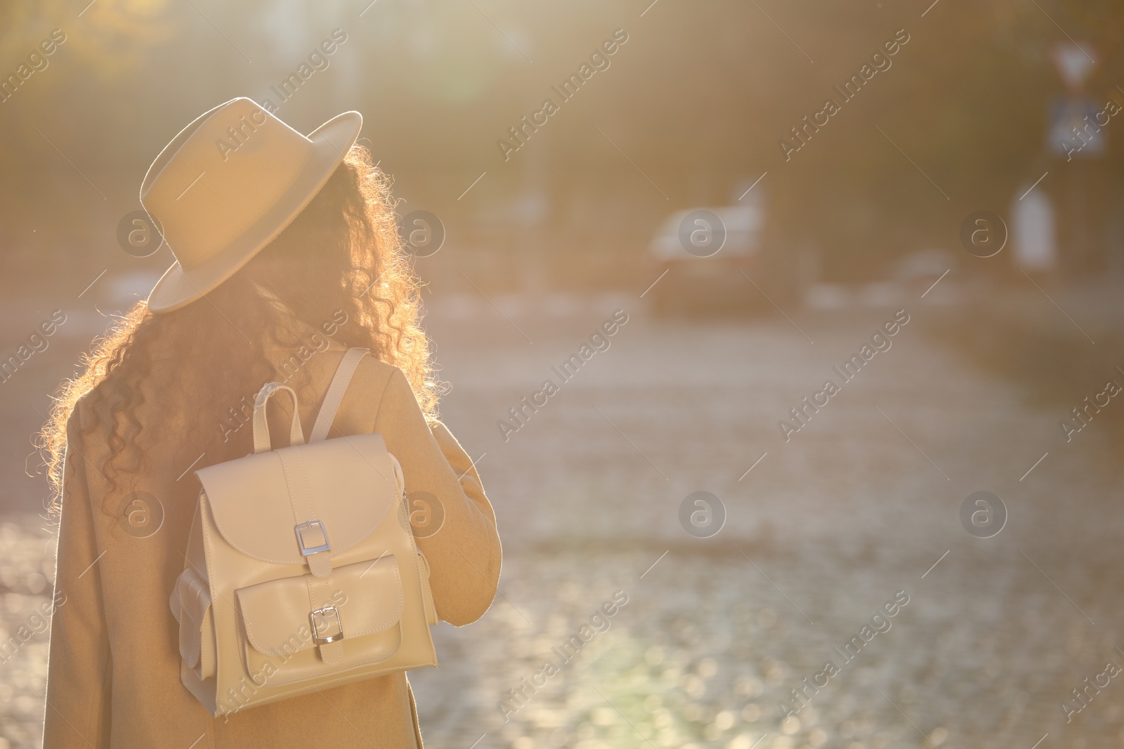 Photo of African-American woman with stylish beige backpack on city street, back view. Space for text