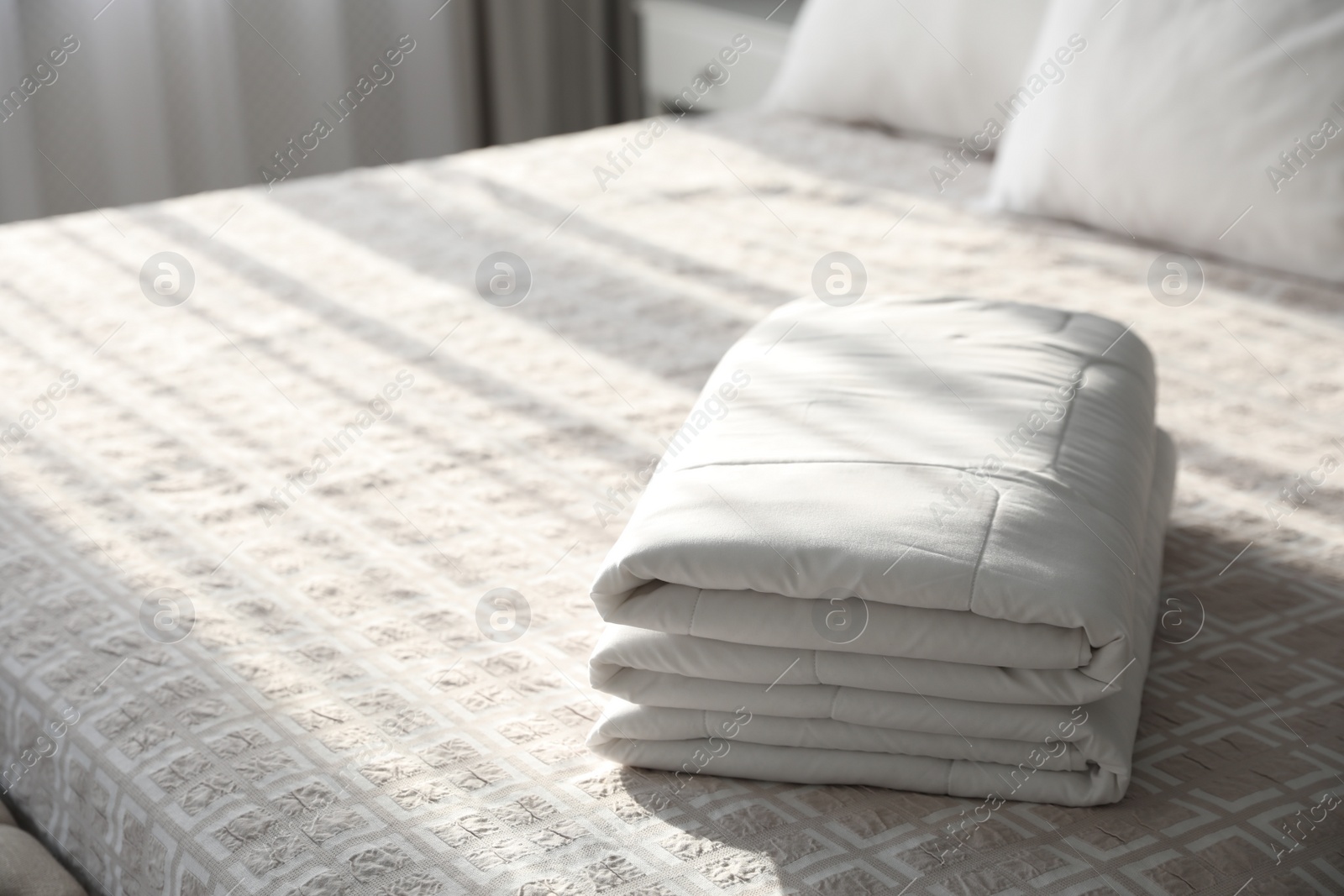 Photo of Folded clean blanket on bed in room. Space for text
