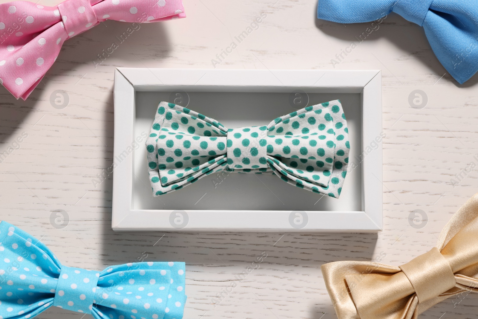 Photo of Stylish color bow ties on white wooden table, flat lay