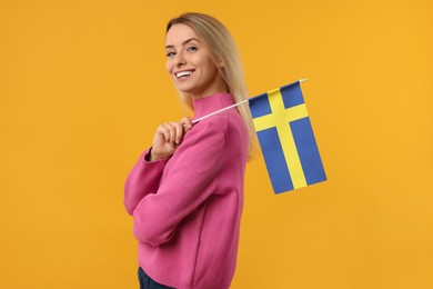 Happy woman with flag of Sweden on orange background