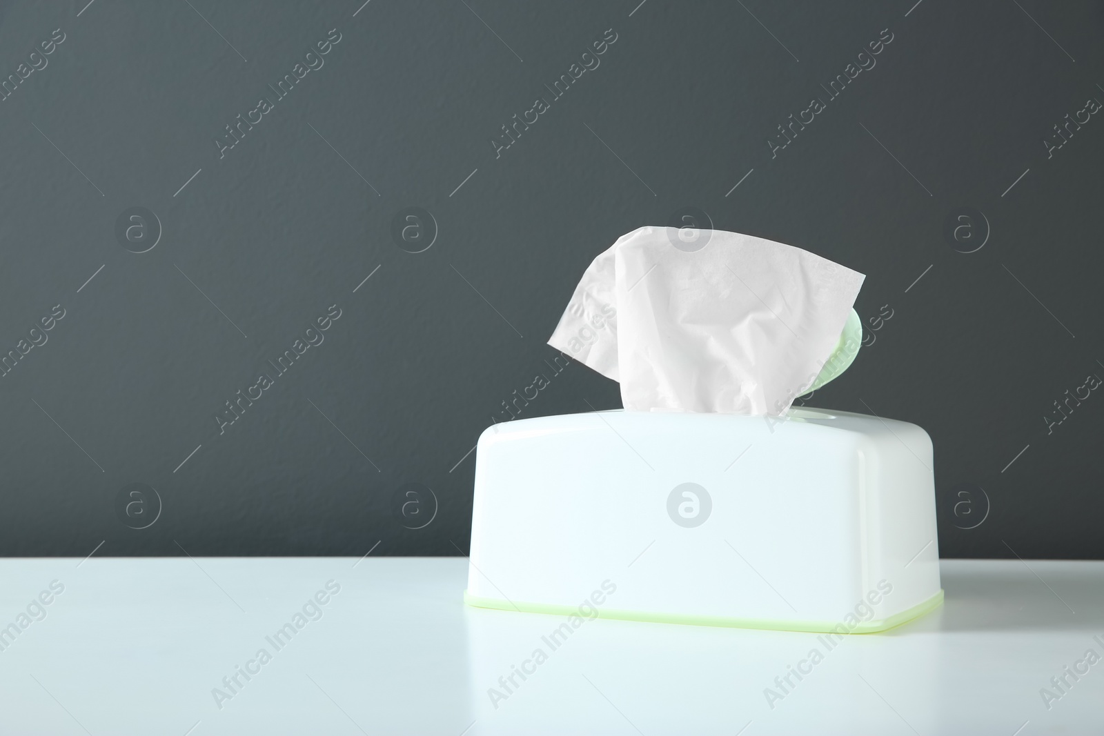 Photo of Holder with paper tissues on white table. Space for text