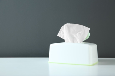 Photo of Holder with paper tissues on white table. Space for text