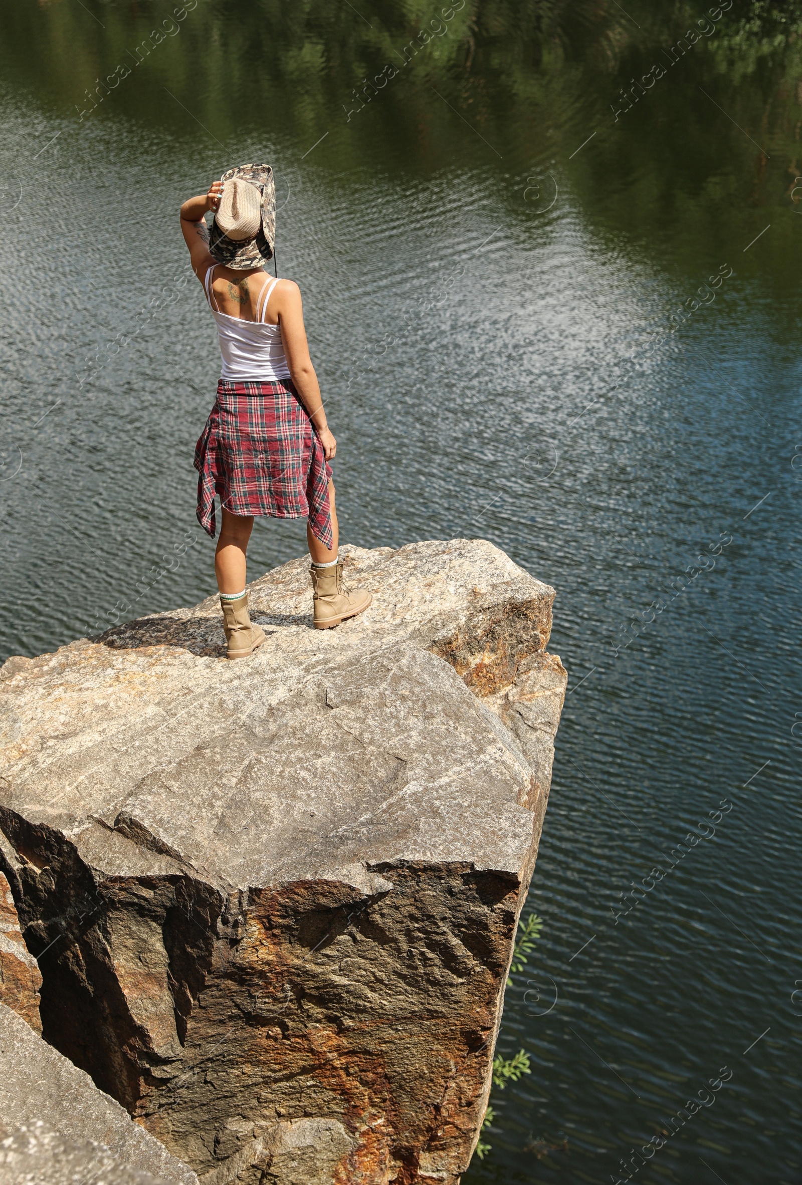 Photo of Young woman on rocky mountain near lake. Camping season