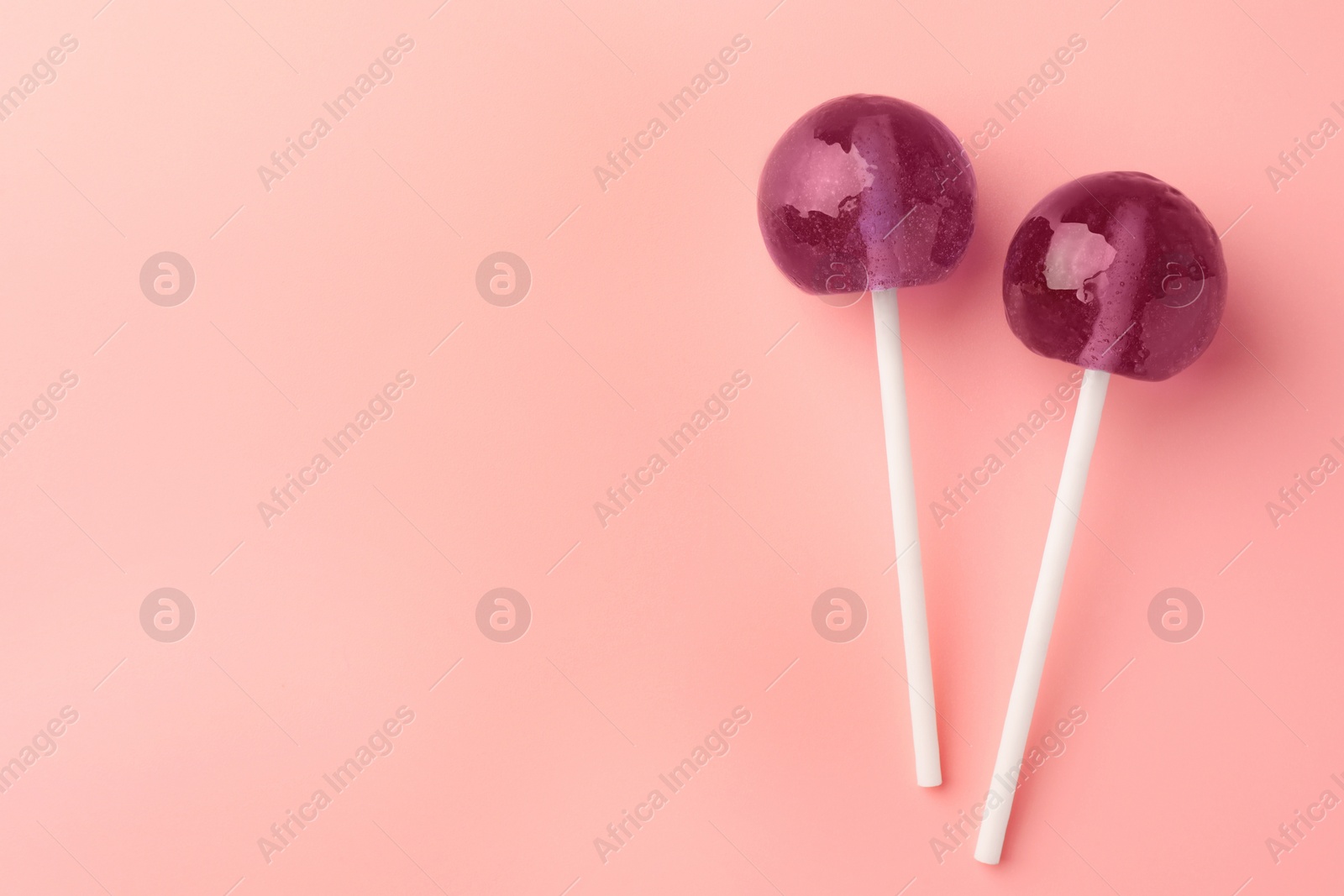 Photo of Tasty lollipops on pink background, flat lay. Space for text