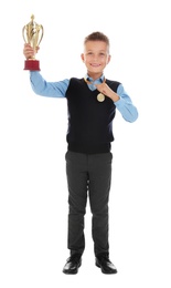 Photo of Happy boy in school uniform with golden winning cup and medal isolated on white
