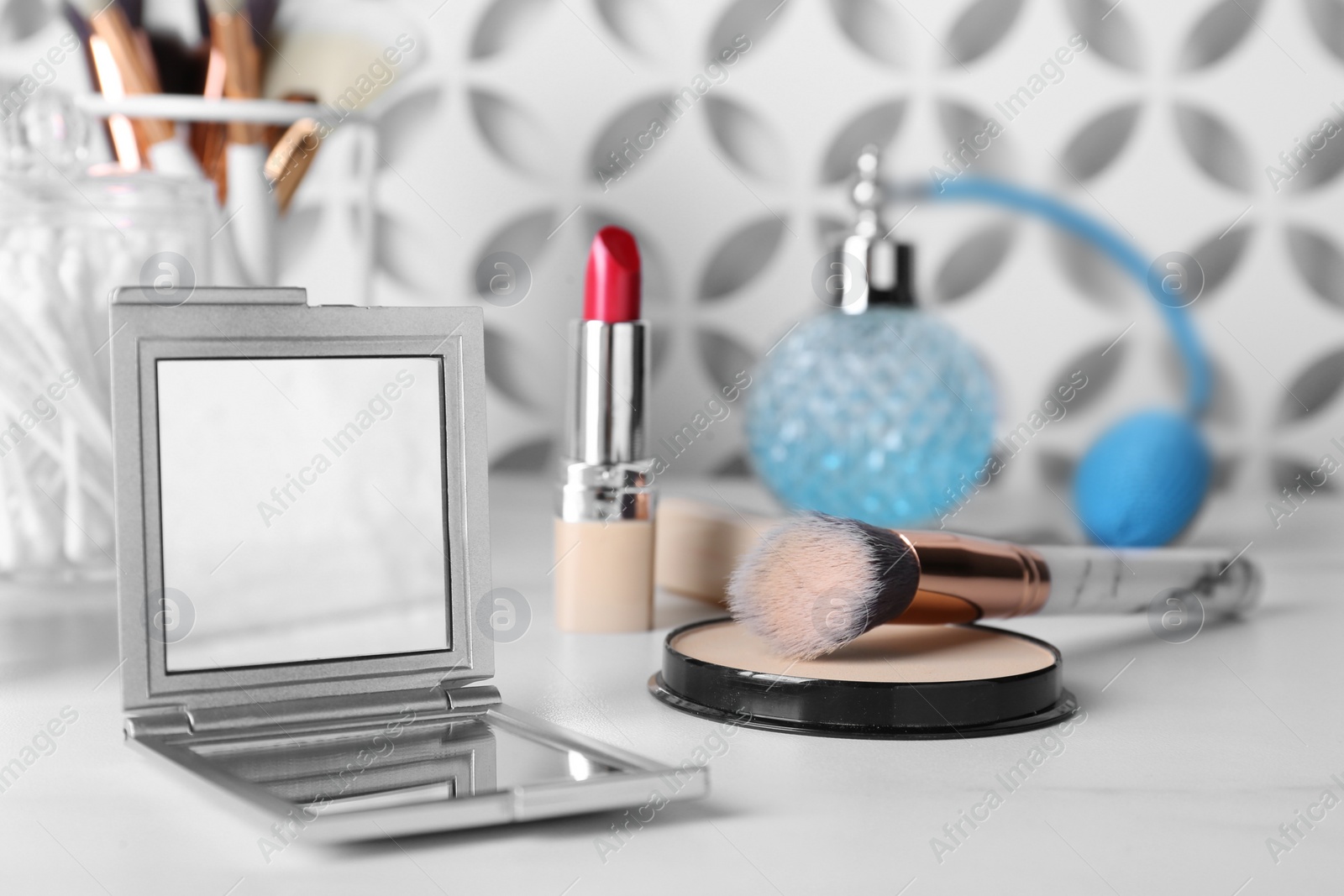 Photo of Stylish pocket mirror and cosmetic products on white table
