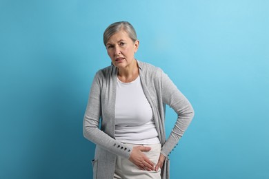 Photo of Arthritis symptoms. Woman suffering from hip joint pain on light blue background