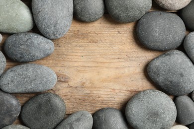 Photo of Frame made with spa stone on wooden table, top view. Space for text