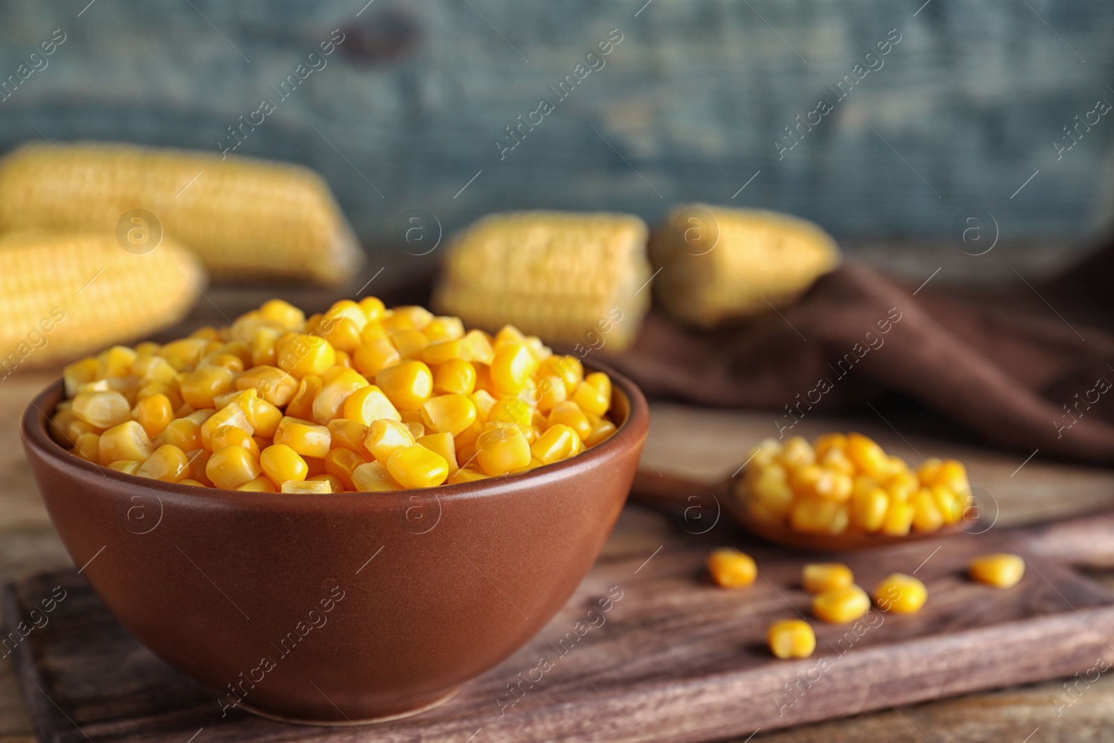 Photo of Delicious canned corn in bowl on wooden table, closeup