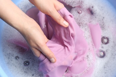 Top view of woman hand washing color clothing in suds, closeup