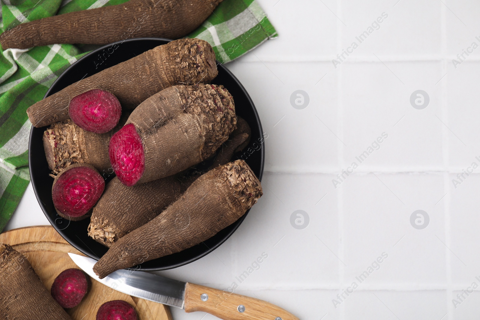 Photo of Bowl with whole, cut red beets and knife on white table, flat lay. Space for text