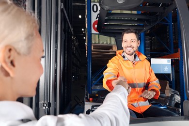 Photo of Happy worker shaking hands with manager in warehouse