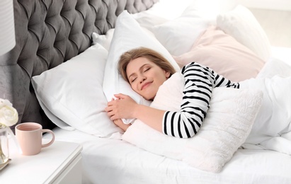 Photo of Young woman embracing pillow while sleeping in bed at home