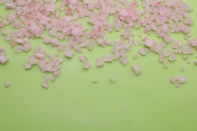 Photo of Pink sea salt on light green background, top view. Space for text