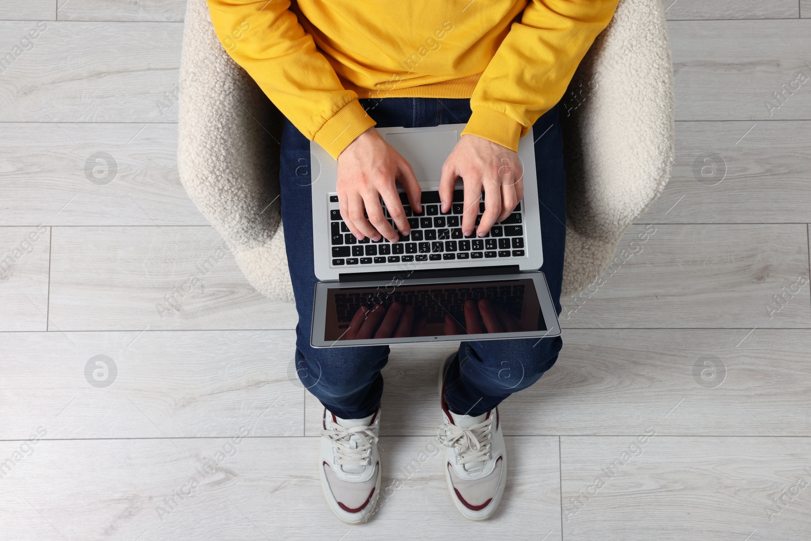 Photo of Man working with laptop in armchair, top view