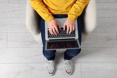 Photo of Man working with laptop in armchair, top view