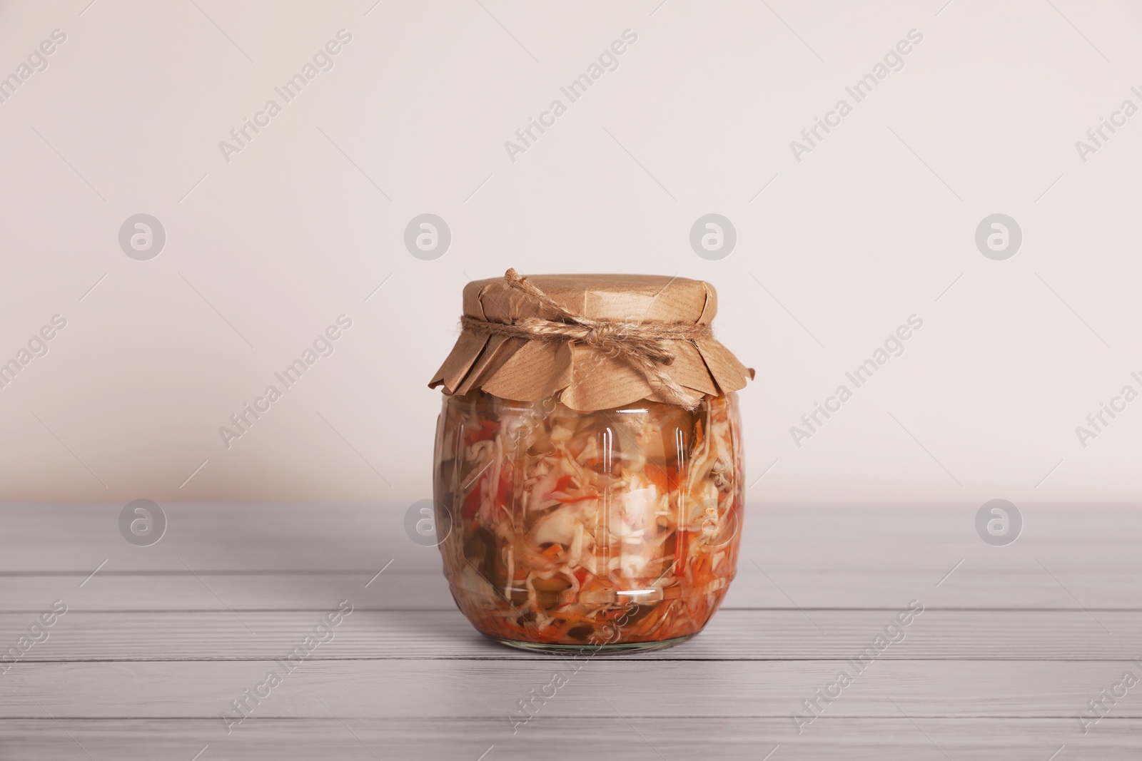 Photo of Jar with preserved cabbage salad on white wooden table