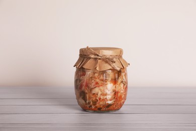 Jar with preserved cabbage salad on white wooden table