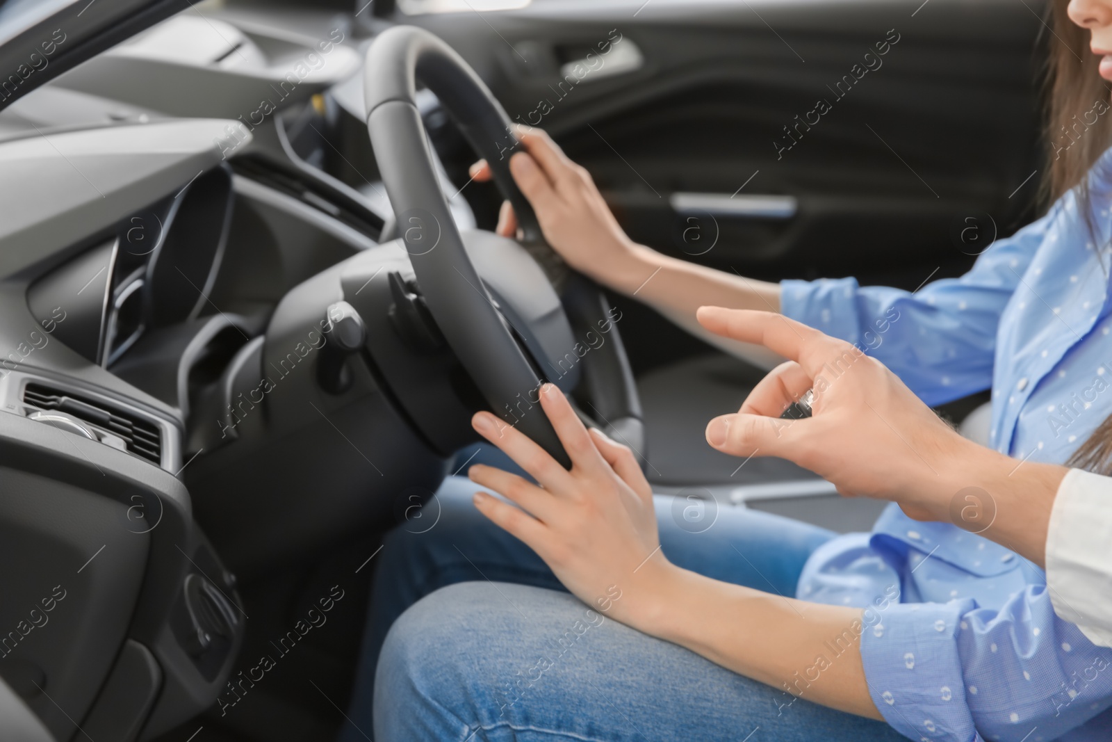 Photo of Salesman consulting young woman in auto at dealership. Buying new car