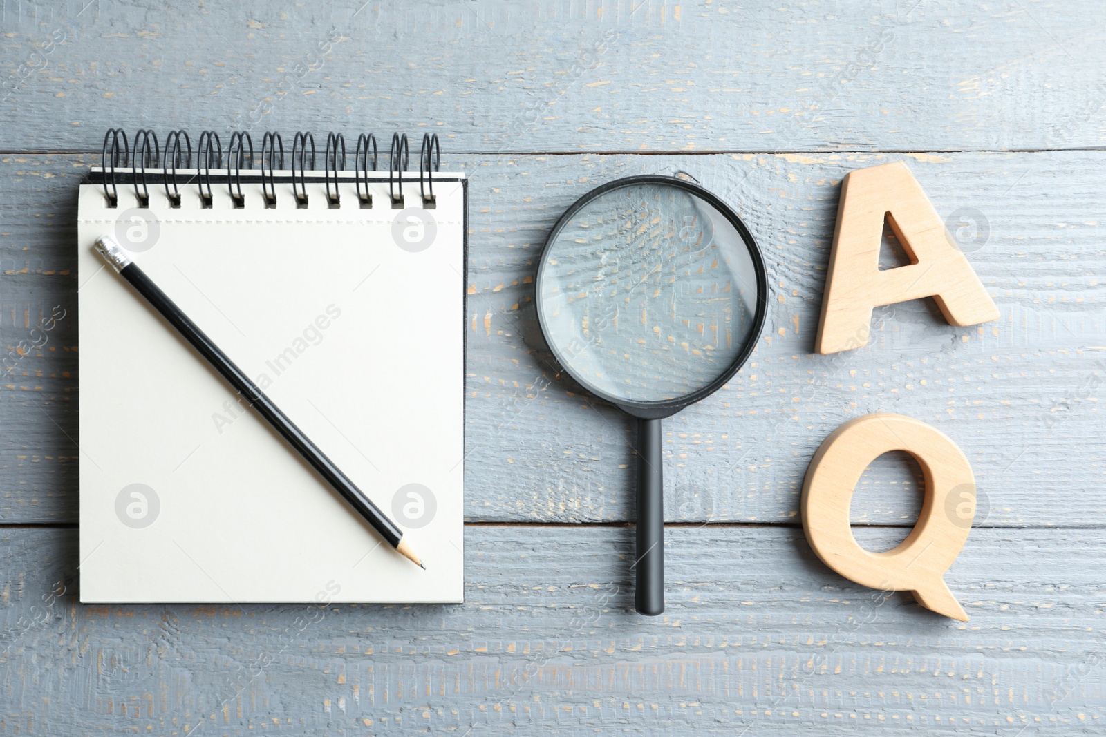 Photo of Flat lay composition with notebook, magnifier glass and letters on light grey wooden table. Find keywords concept