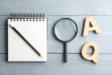 Flat lay composition with notebook, magnifier glass and letters on light grey wooden table. Find keywords concept