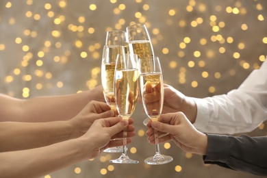 People clinking glasses of champagne on blurred background, closeup