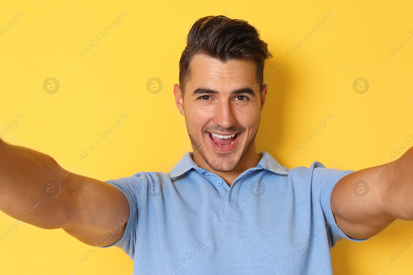 Photo of Handsome young man taking selfie on color background
