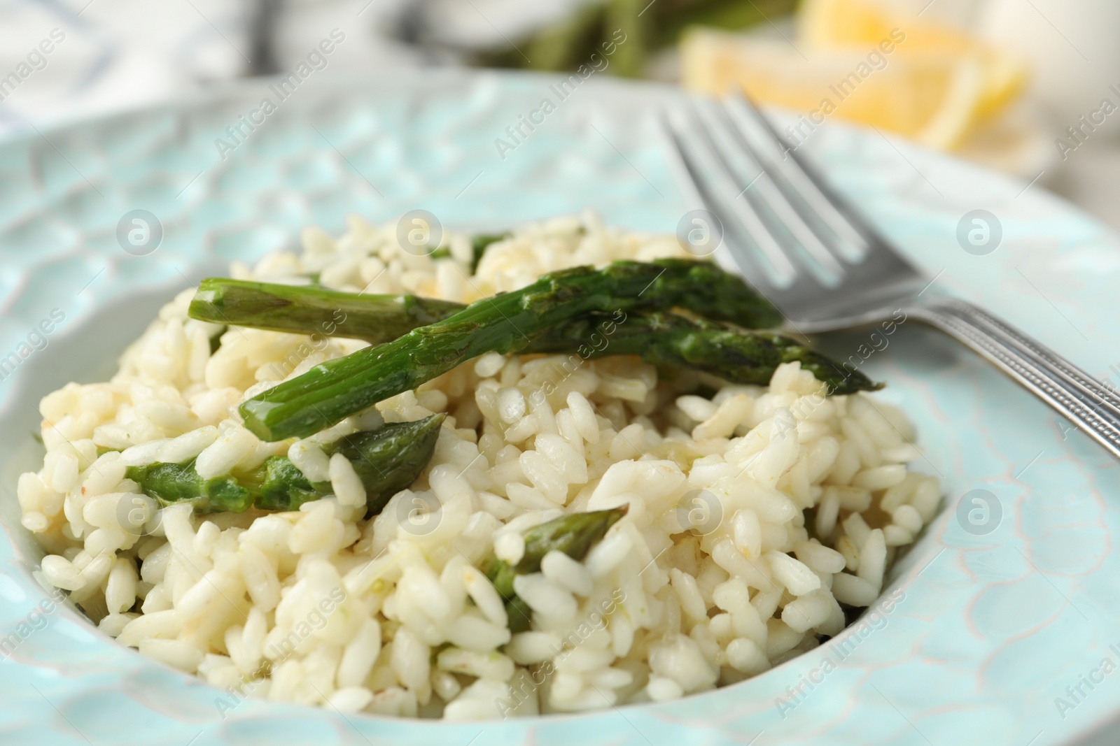 Photo of Delicious risotto with asparagus in plate, closeup