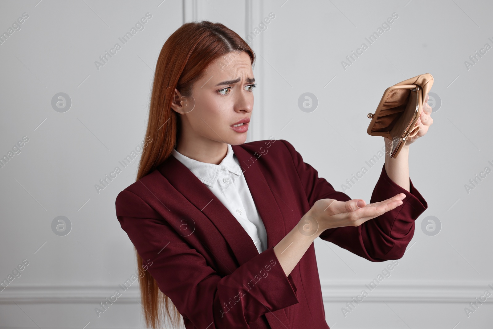 Photo of Upset woman with empty wallet near white wall