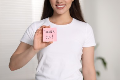 Photo of Woman holding paper note with phrase Thank You indoors, closeup