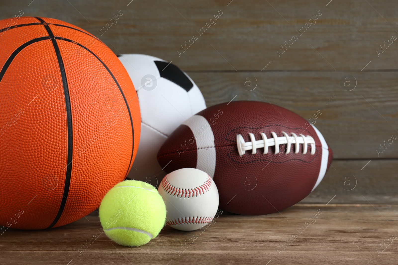 Photo of Set of different sport balls on wooden table, closeup