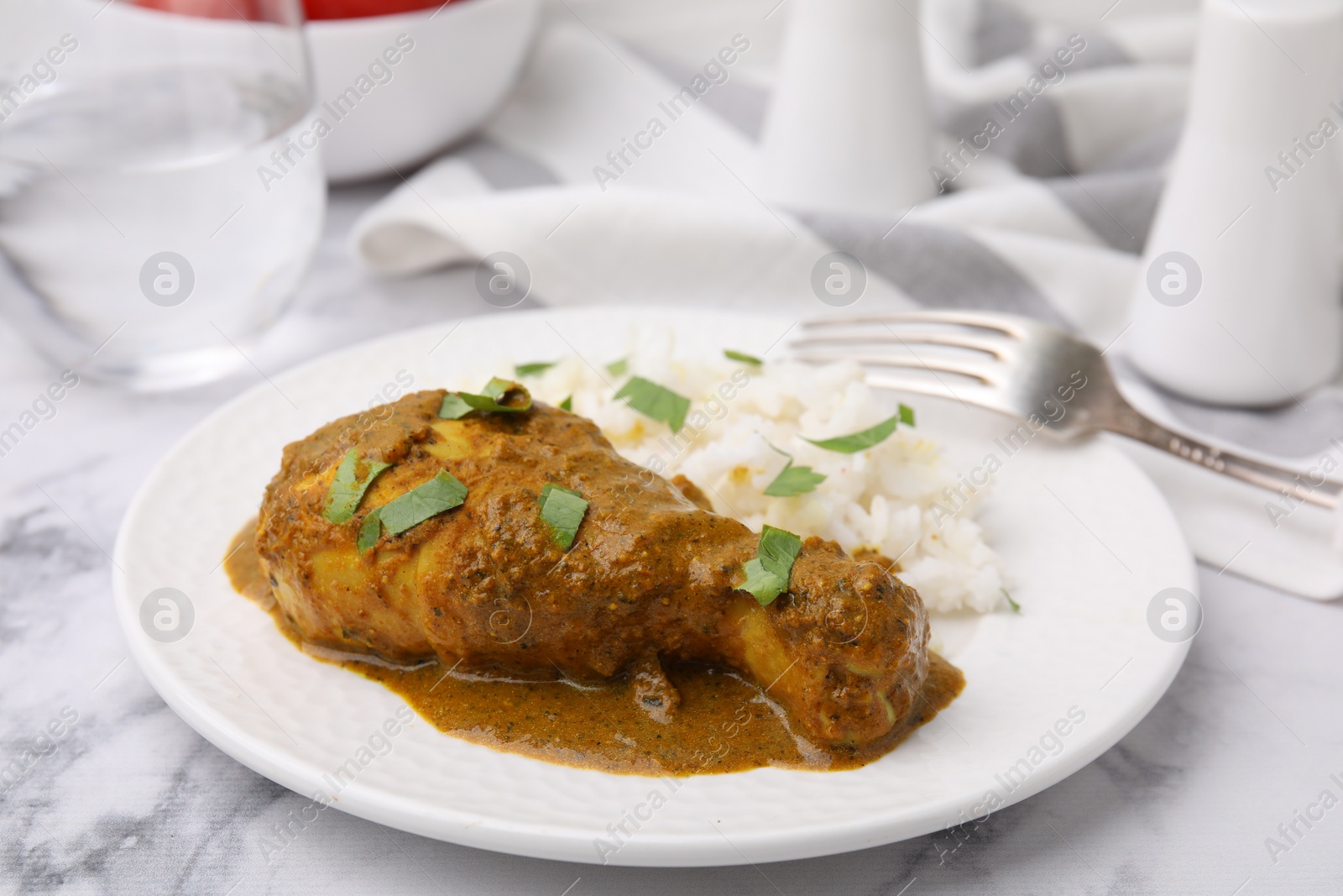 Photo of Delicious rice and chicken with curry sauce served on white marble table, closeup