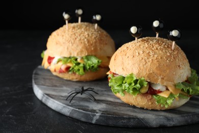 Photo of Cute monster burgers served on black table. Halloween party food