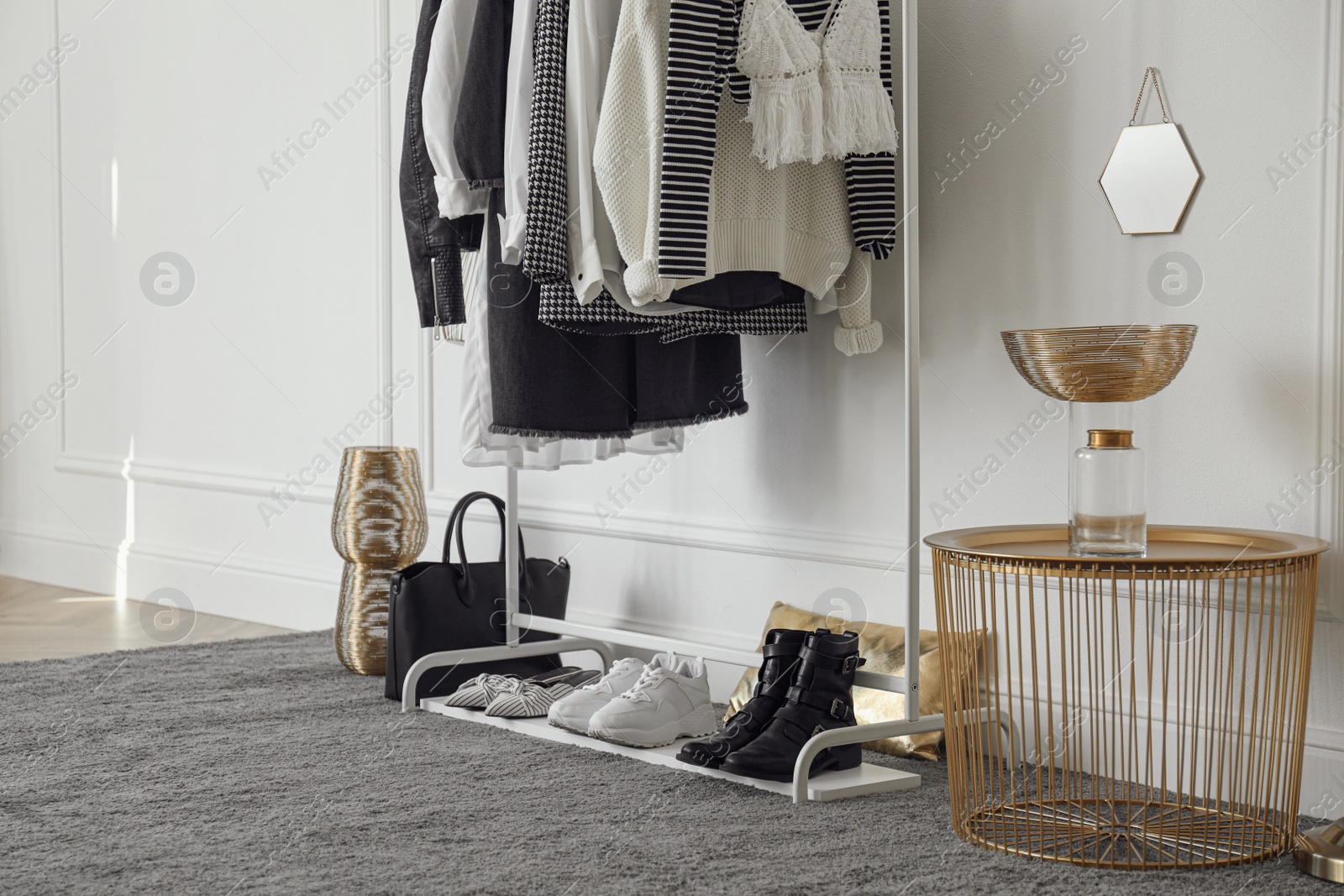 Photo of Rack with stylish clothes near white wall in dressing room