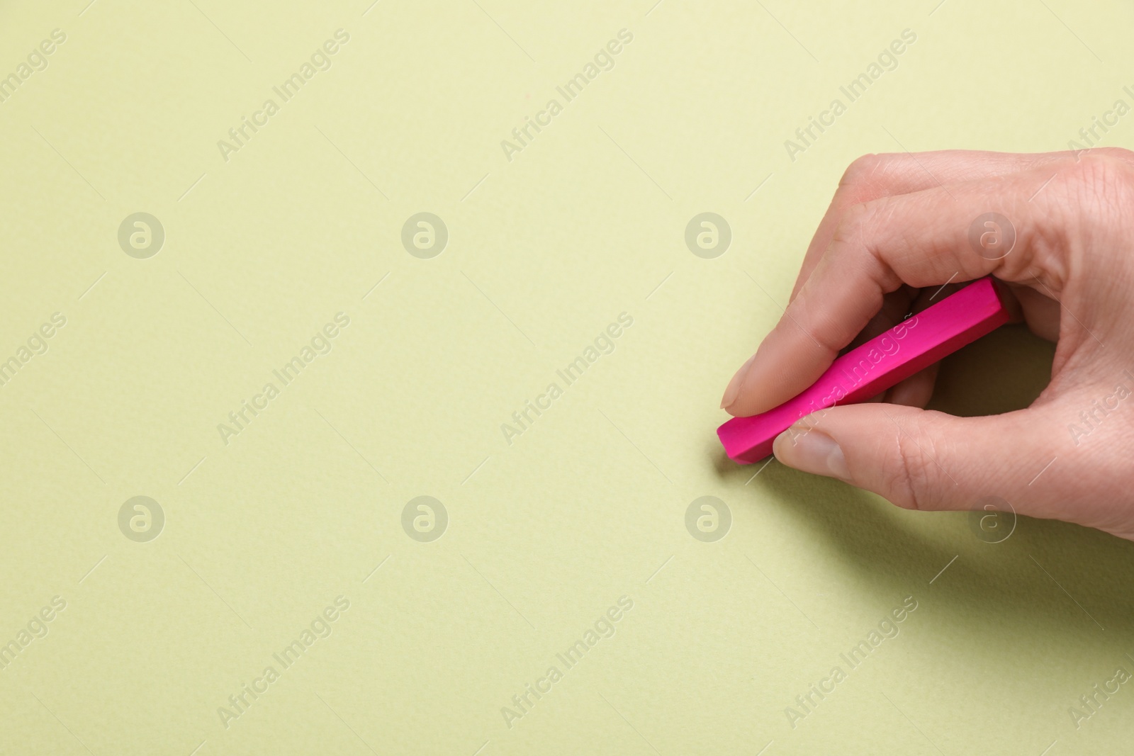 Photo of Woman drawing on light green paper with pastel, closeup. Space for text