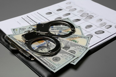 Photo of Composition with fingerprints, cash and handcuffs on grey background, closeup