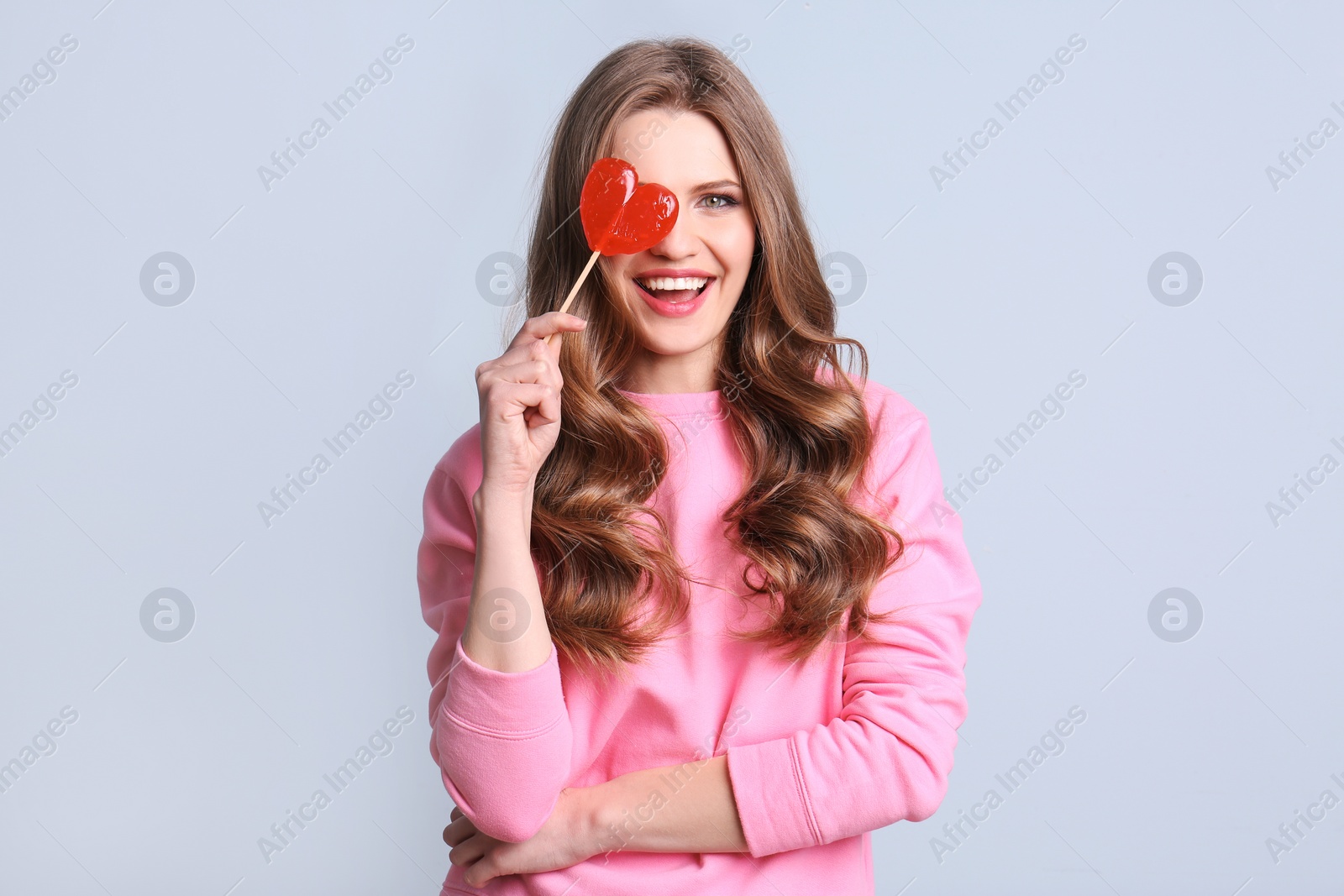 Photo of Portrait of young woman with long beautiful hair and lollipop on color background