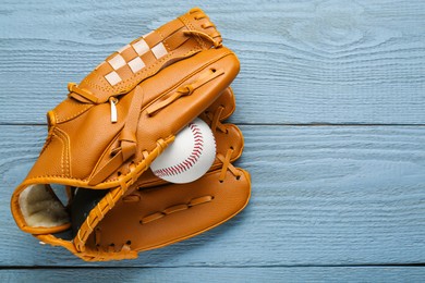 Photo of Leather baseball glove with ball on grey wooden table, top view. Space for text