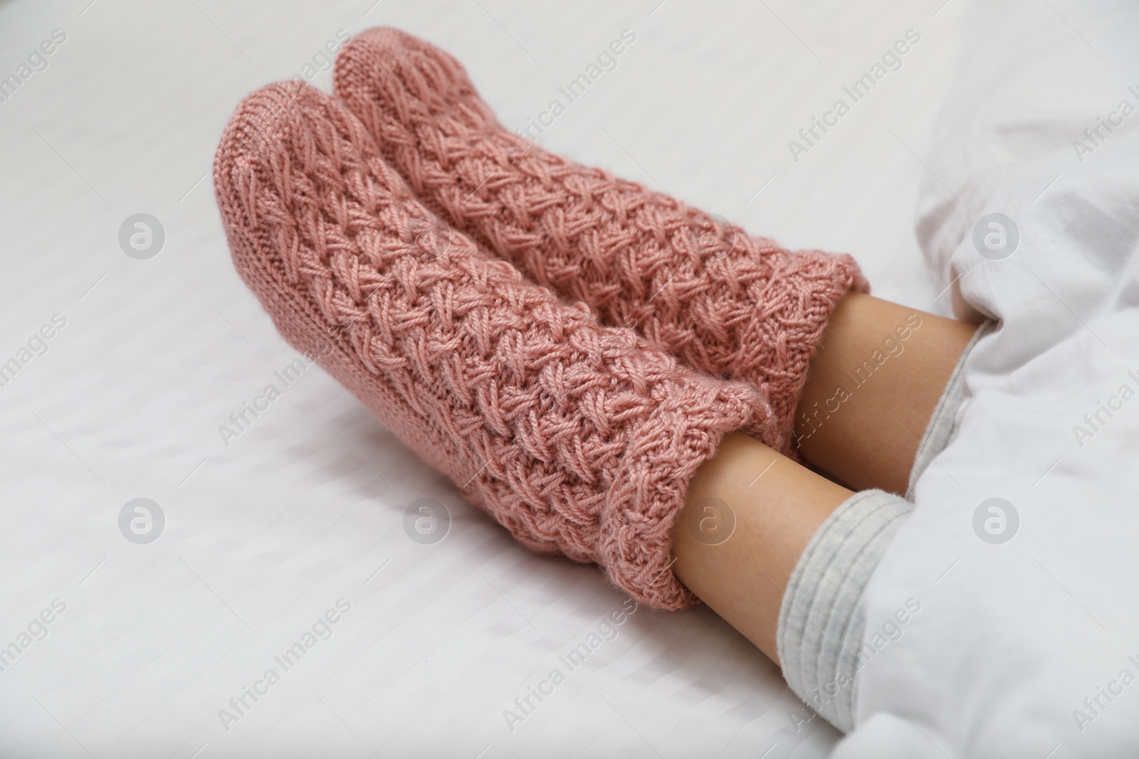 Photo of Woman wearing pink warm socks in comfortable bed, closeup