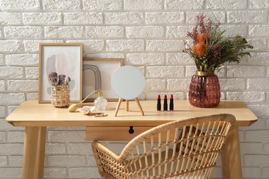 Photo of Mirror, makeup products and perfume on dressing table in room