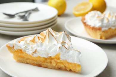 Plate with piece of delicious lemon meringue pie on light table