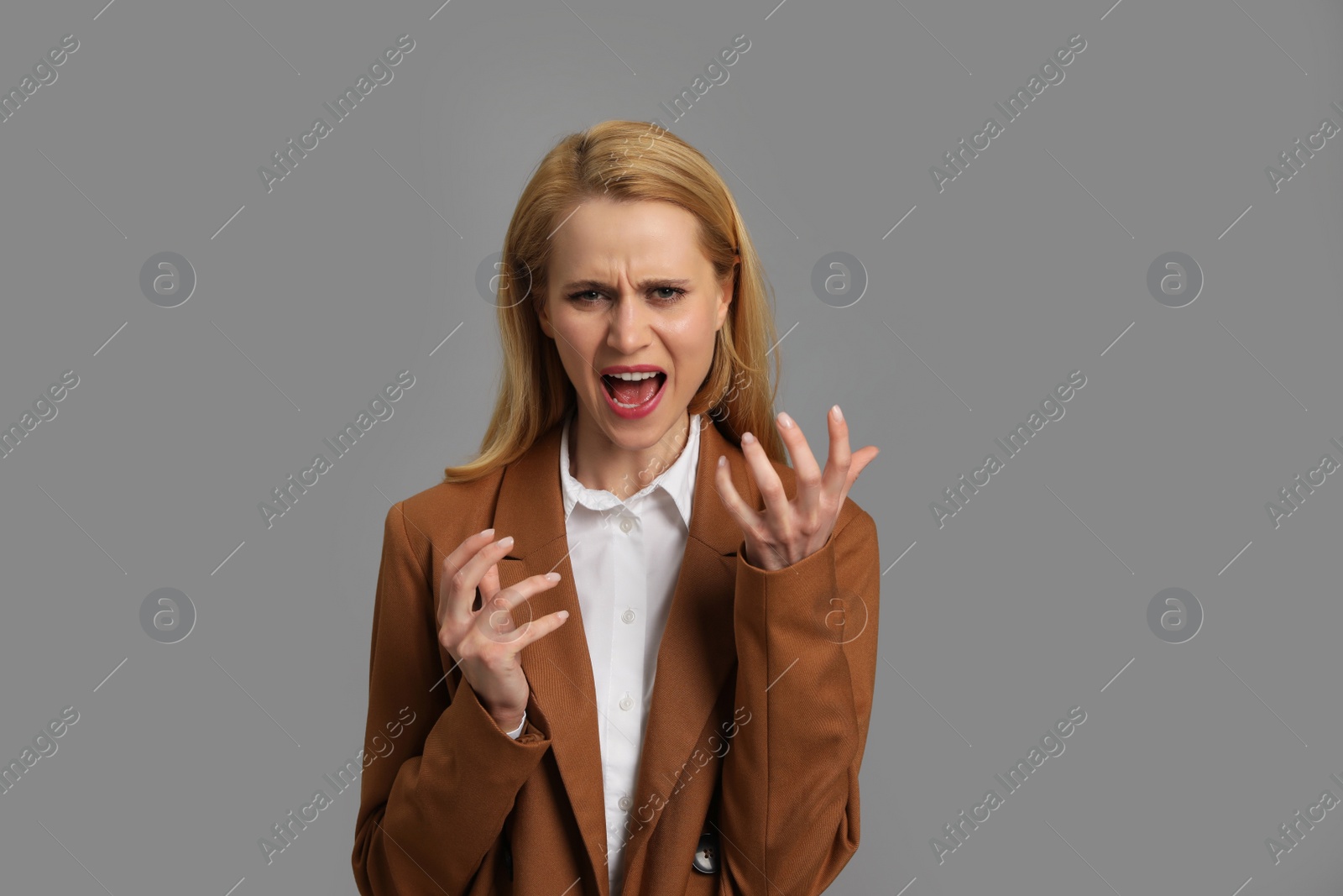 Photo of Angry young woman on grey background. Hate concept