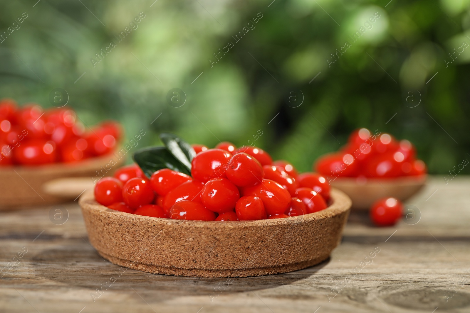 Photo of Plate with fresh goji berries on wooden table against blurred background. Space for text